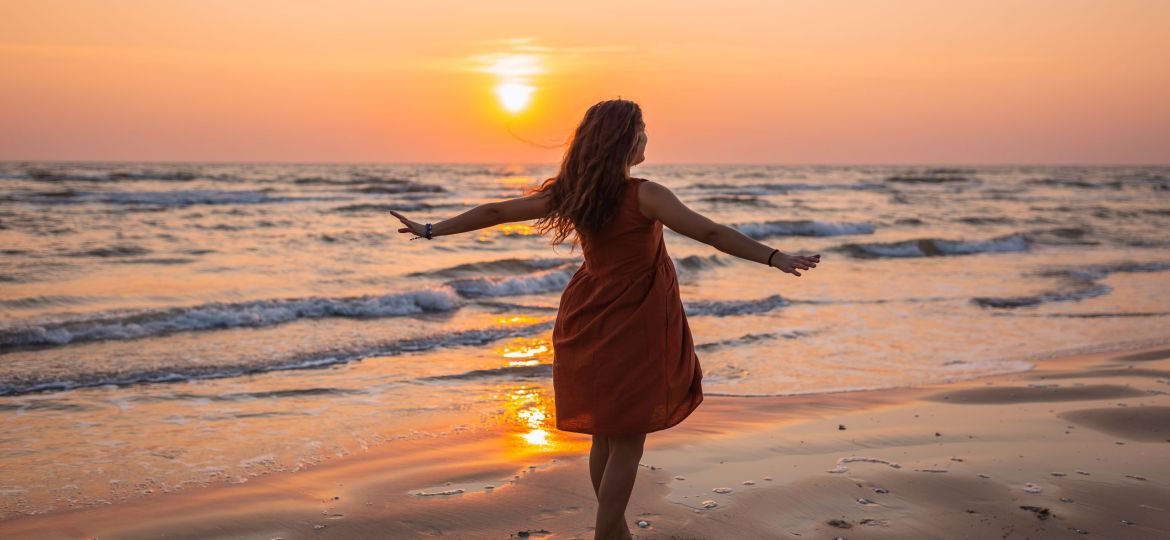 Beautiful shot of a model wearing a brown sundress enjoying the sunset  at the beach