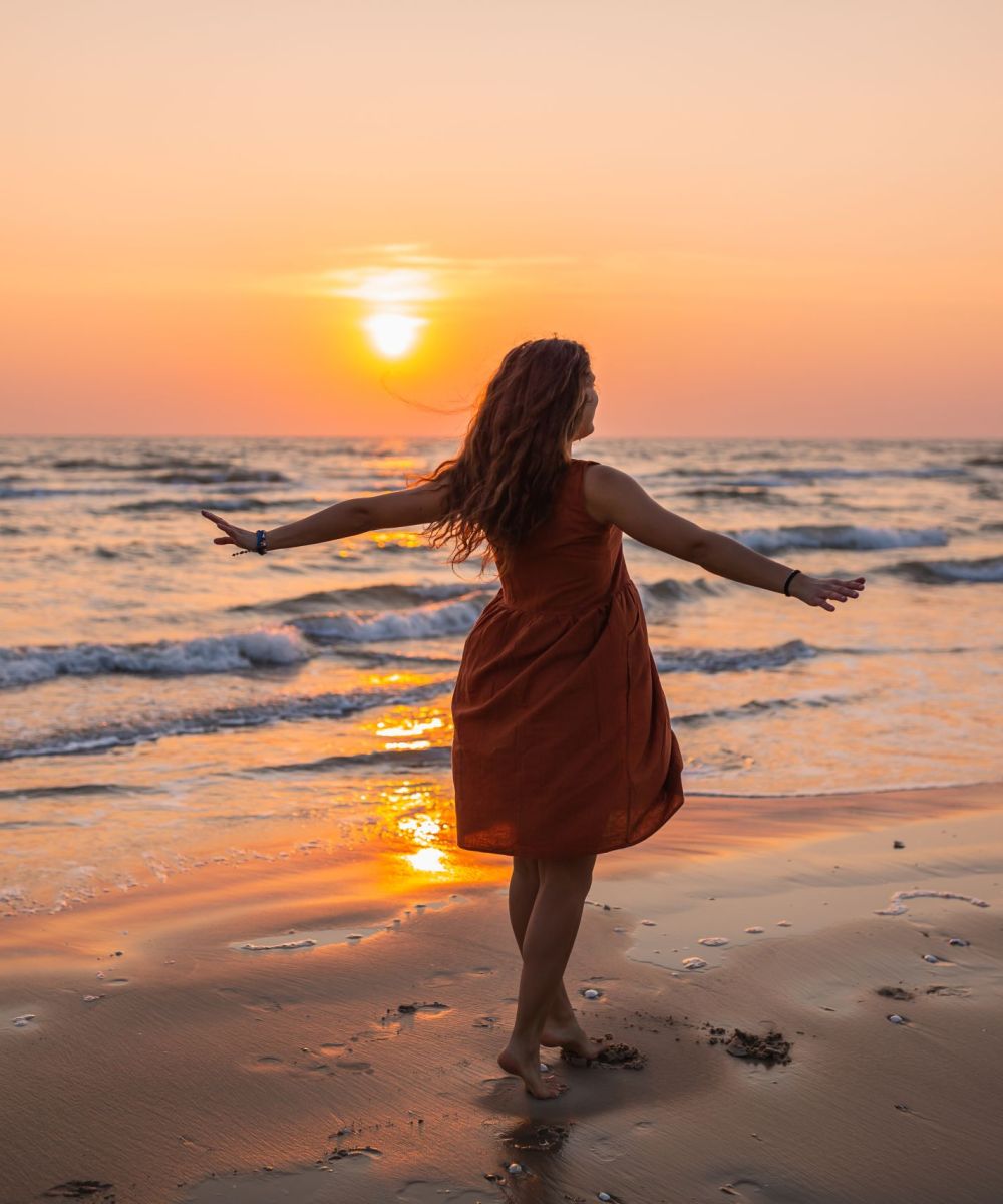 Beautiful shot of a model wearing a brown sundress enjoying the sunset  at the beach