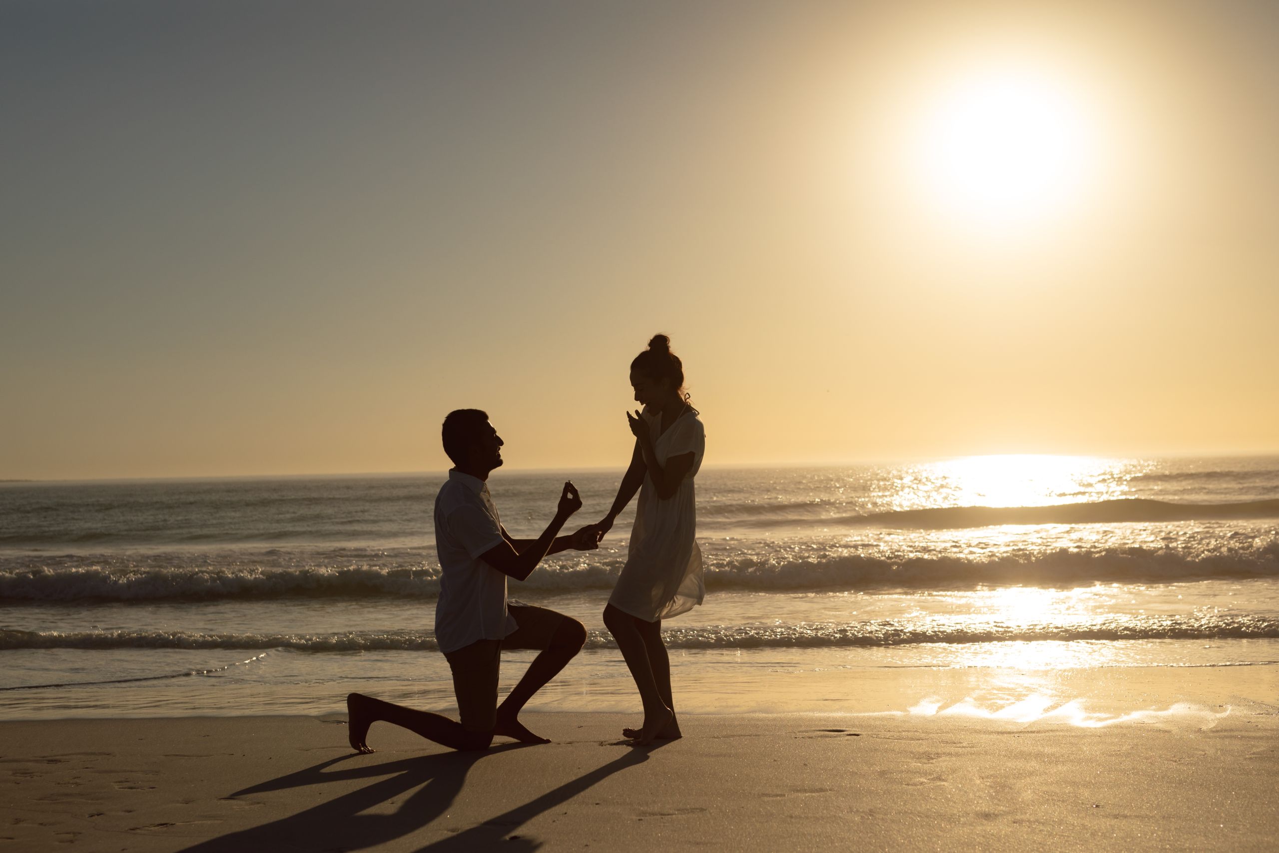 Romantic man proposing woman at seashore on the beach